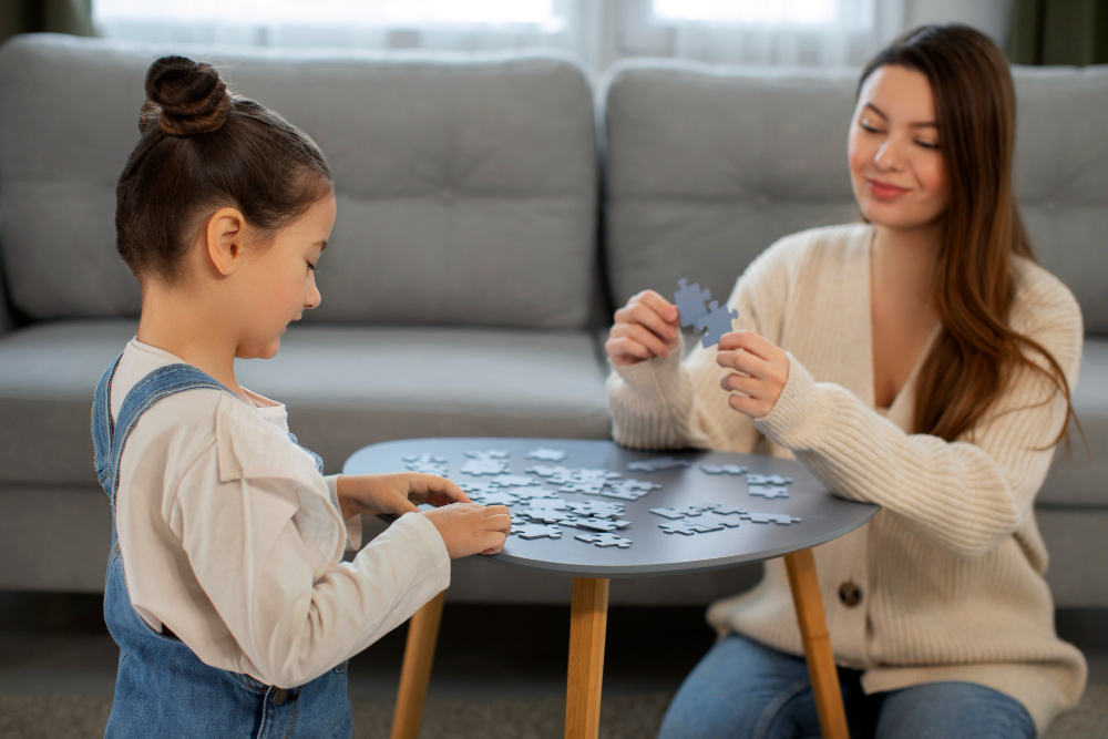 Girl and therapist working on a puzzle together at a small table